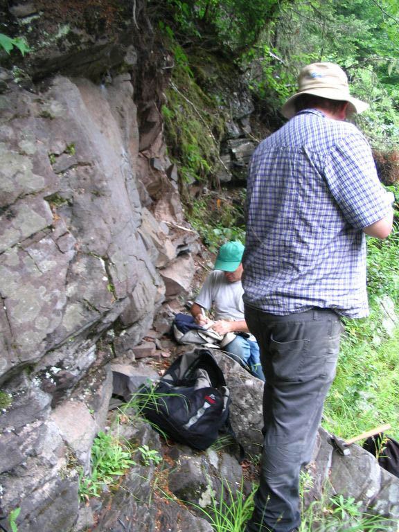Colour photograph of two men near rock face