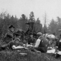 Black and white photograph of camp site with five men, carriages and horses