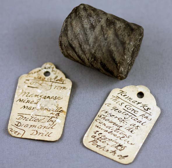Image couleur de roche noire cylindrique et deux étiquettes d’identification manuscrites