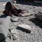 Photographie couleur de rochers sur une plage avec un sac à dos et la moitié d’une pierre grise circulaire