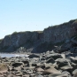 Photographie couleur d’une plage avec de hautes falaises grises