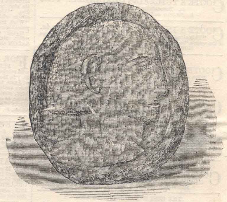 Black and white print of round stone with carved face in profile