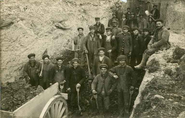 Black and white photograph of several men with shovels and wagon loaded with rocks