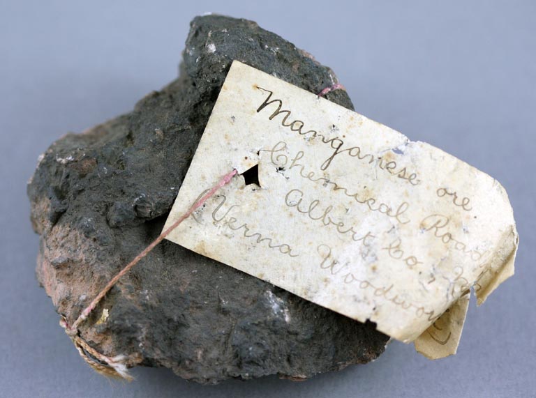 Colour image of black rock with white spots and handwritten label tied on with pink string