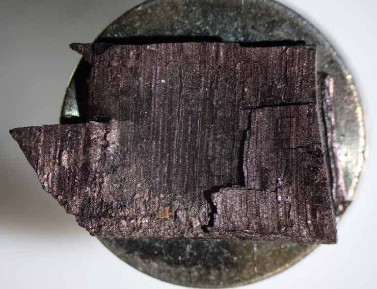 Colour photograph of a small piece of red rock glued to a silver metal disk