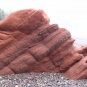 Colour photograph of a red sandstone rock on the beach
