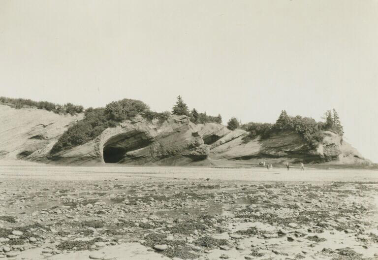 Photographie noir et blanc de l’océan devant une falaise rocheuse