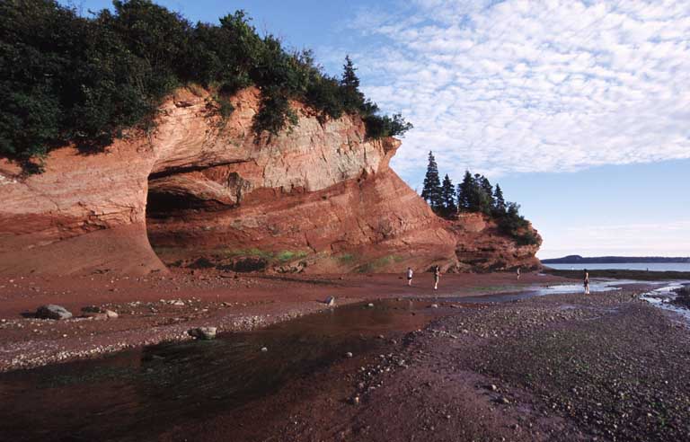 Photographie couleur d’une falaise en roche rouge au bord de l’océan