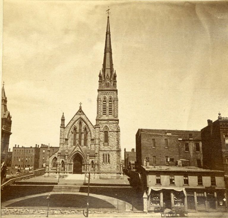 Black and white photograph of stone church with steeple on right