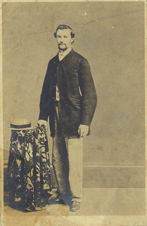 Black and white photograph of man standing by a table