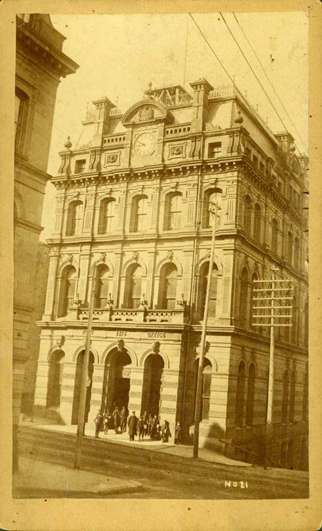 Black and white photograph of four storey stone building with mansard roof