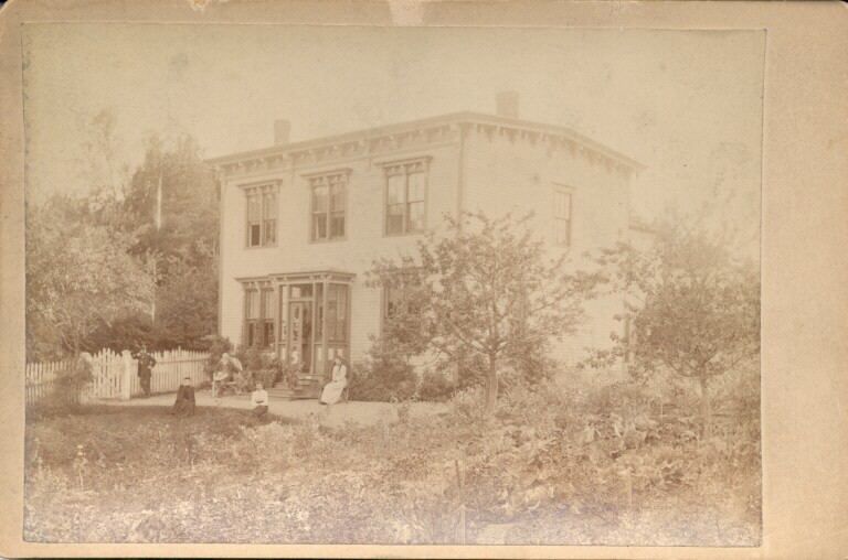 Black and white photograph of two storey house and front garden