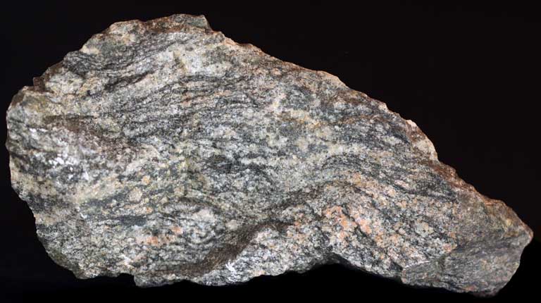 Colour image of gray rock with black, green and pink spots and streaking