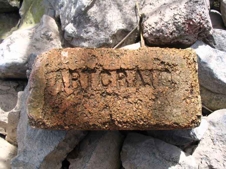 Photographie couleur d’une vieille brique portant l’inscription gravée ARTCRAF