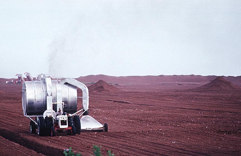 Colour photograph of a man driving a tractor in brown field