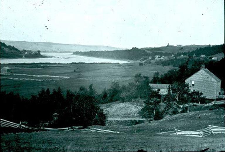 Black and white photograph of a building with a river behind and with trees on both sides 
