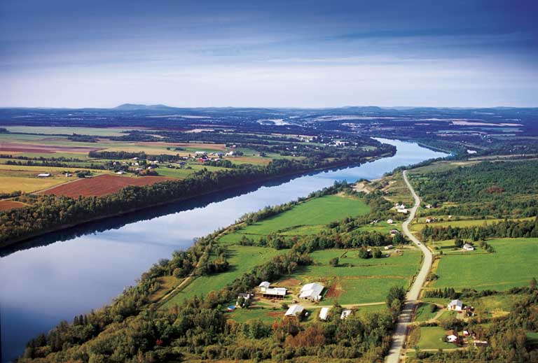 Colour photograph of a river with green fields on both sides