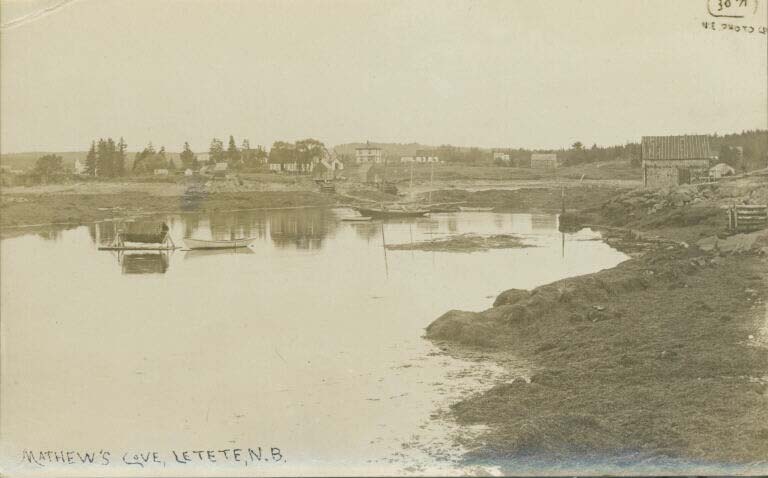 Carte postale noir et blanc montrant un rivage rocailleux à marée basse, l'eau, des bateaux et des maisons