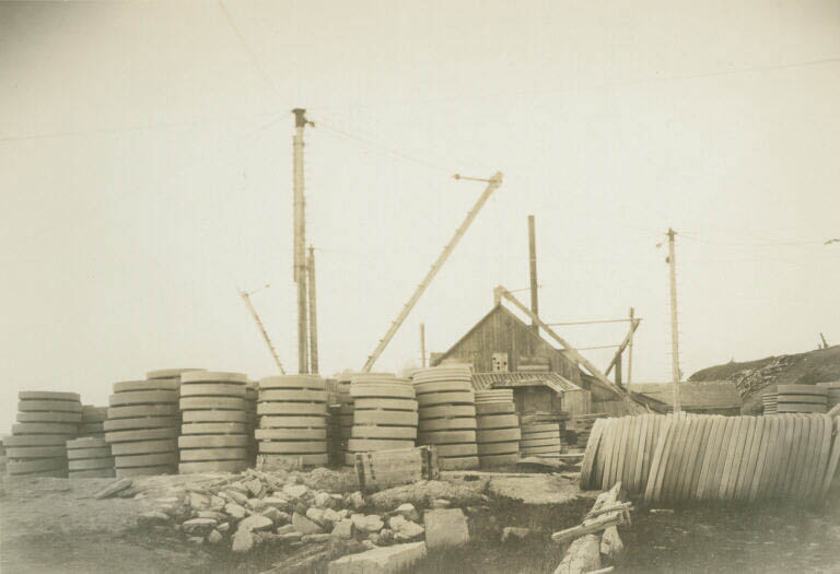Black and white photograph of an old stone quarry with cranes and blocks of stone