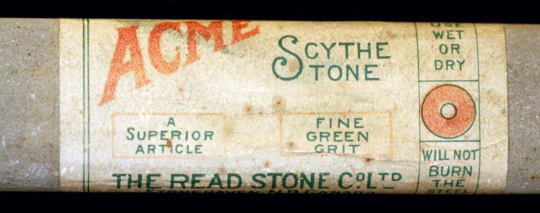 Colour photograph of a label ‘ACME Scythe Stone’ on a gray rock