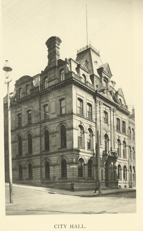Black and white photograph of an old four-storey building on a street corner