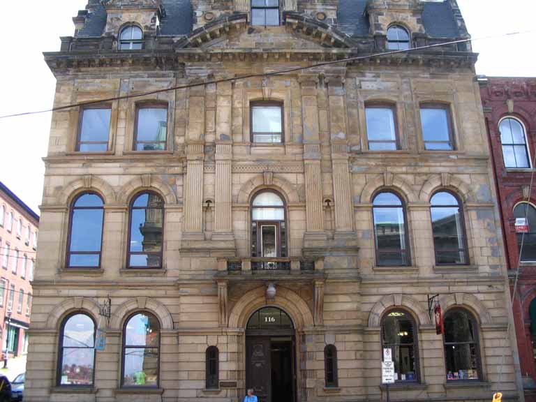 Colour photograph of an old brown sandstone four-storey building on a street