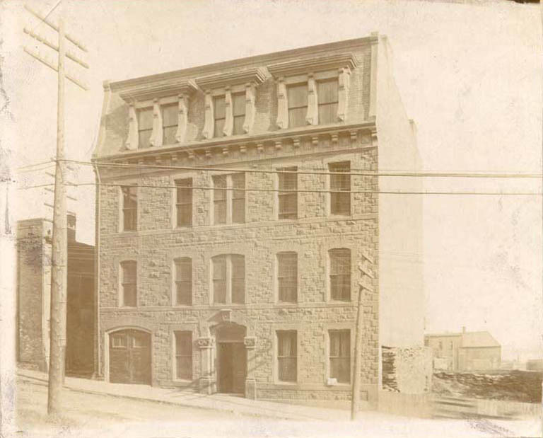 Black and white photograph of a old four-storey building with windows facing the street