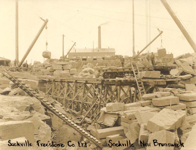 Black and white photograph of an old stone quarry with cranes and blocks of stone