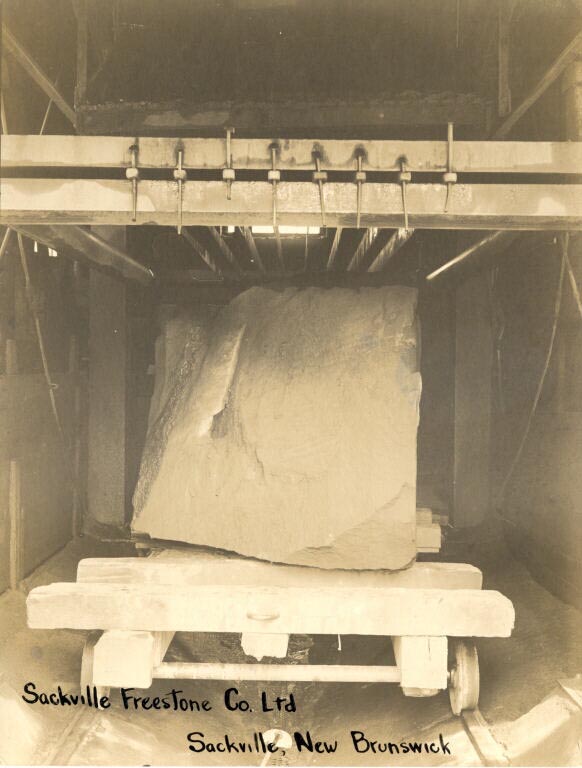 Black and white photograph of a large sandstone block sitting on a wooden platform