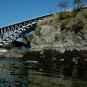 Colour photograph of bridge steelwork, river and rock face