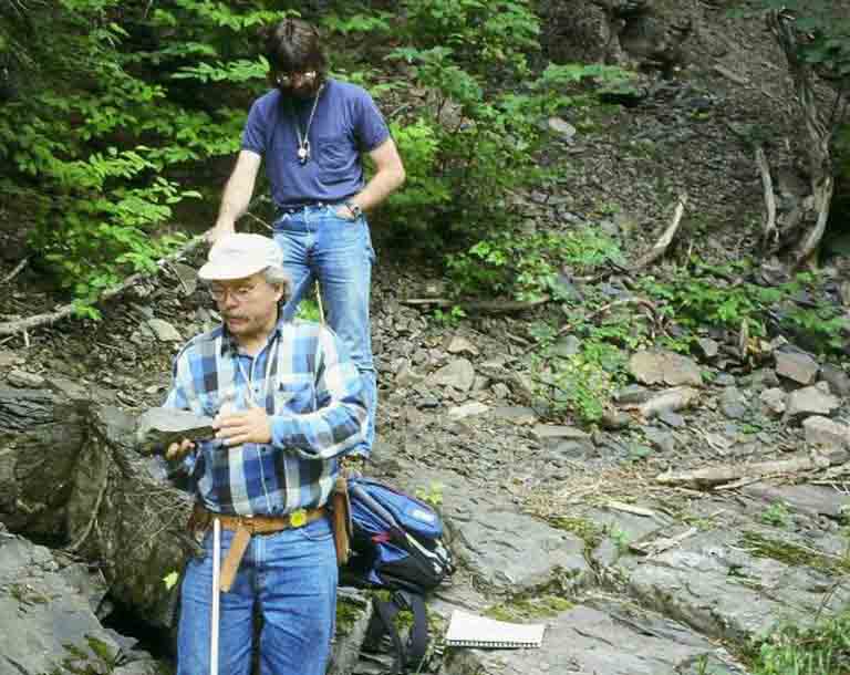 Colour photograph of two men near rock face