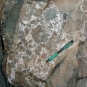 Colour photograph of brown rock with white and black spots and pencil for scale
