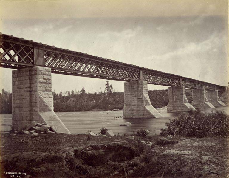 Black and white photograph of a railway bridge with granite piers over a river