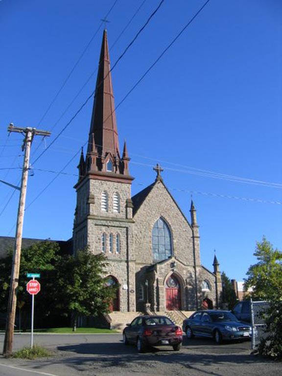 Colour photograph of stone church with large steeple on left