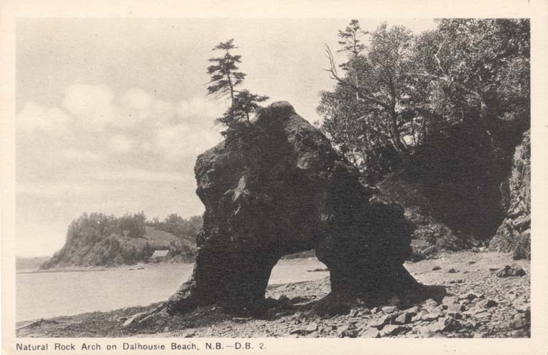 Black and white postcard of rocky beach with curved rock formation with hole in the centre