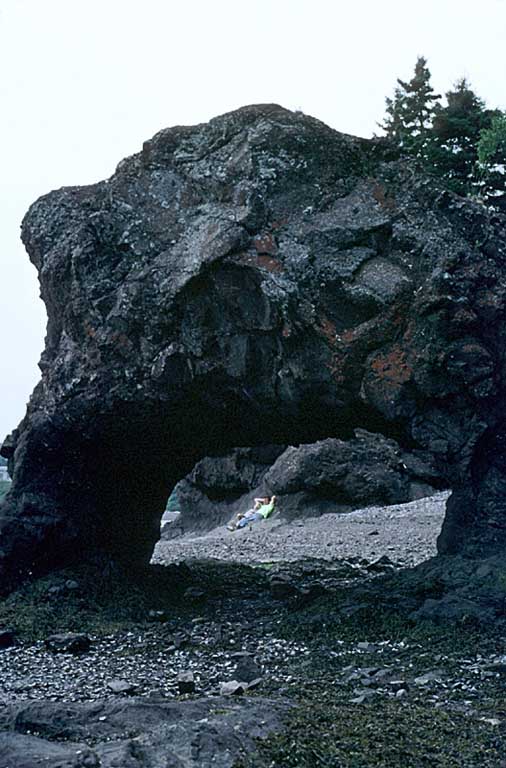 Colour photograph of arched rock formation with hole in centre