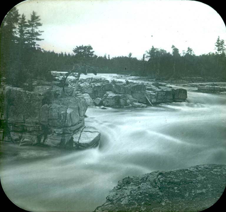Image noir et blanc de la rivière passant entre des falaises et saillies rocheuses