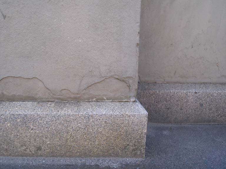 Photographie couleur d’une dalle de roche grise à la base de la colonne d’un édifice