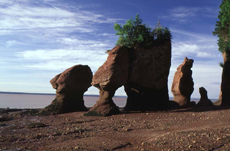 Colour photograph of tall red rock formations on a beach