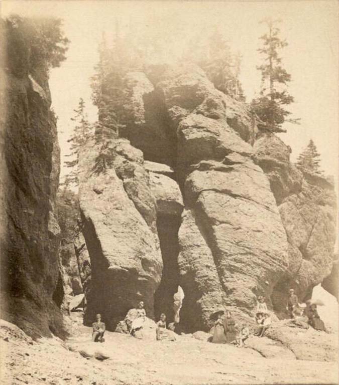 Black and white photograph of tall rock formations and people on beach