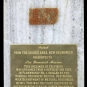 Colour image of white marble plaque with bronze text panel and orange rock with white and gray spots