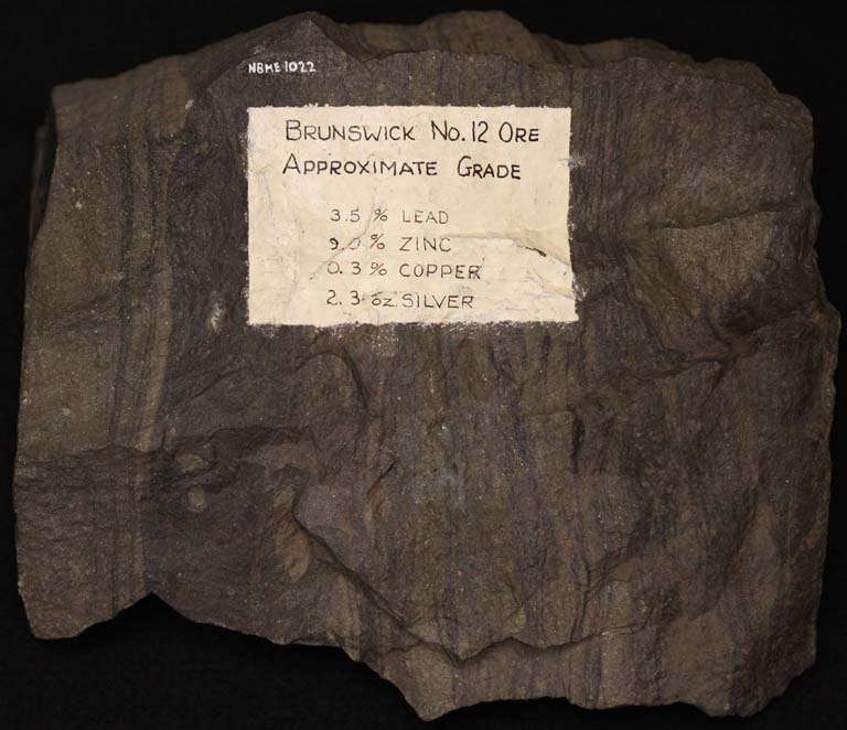 Colour image of brown rock with vertical striping and paper label
