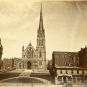 Black and white photograph of stone church with steeple on right