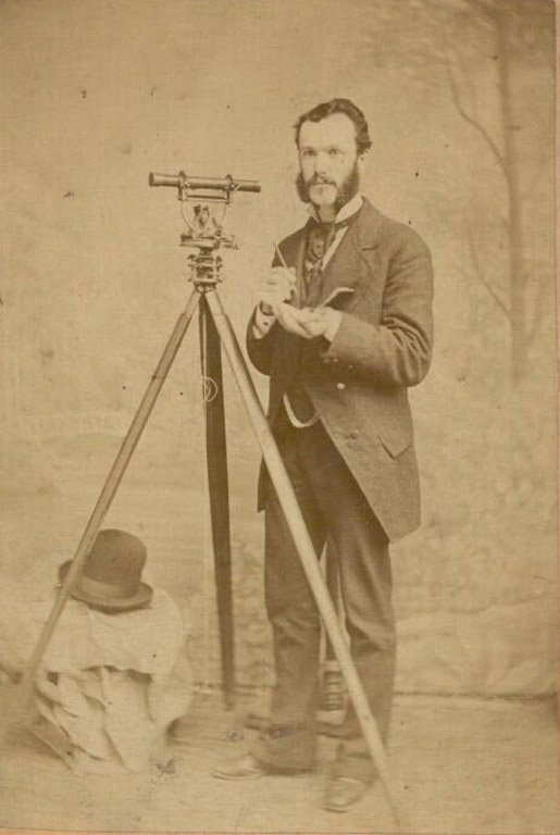 Black and white photograph of a man standing with a telescope