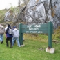 Colour photograph of rock face, people and green sign