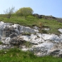 Colour photograph of rocks, green grass and sky