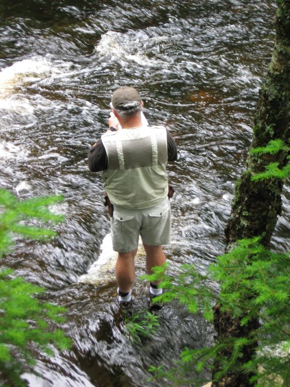 Photographie couleur d’un homme debout dans un ruisseau