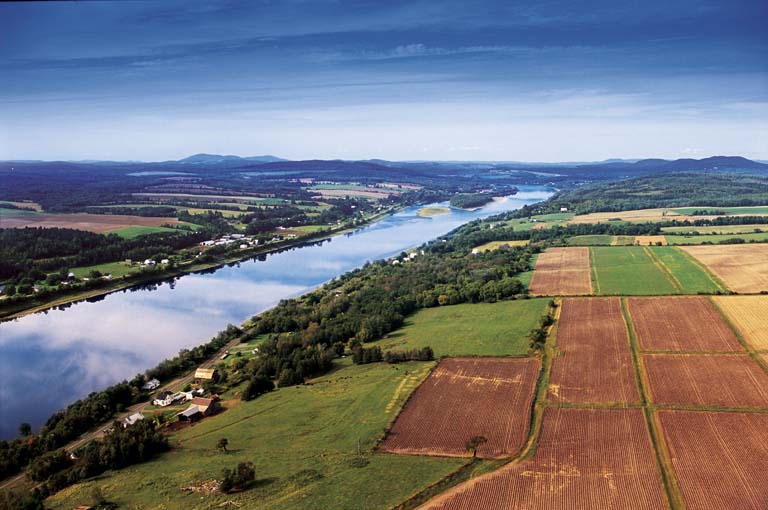 Photographie couleur d’un cours d’eau qui traverse des champs verdoyants