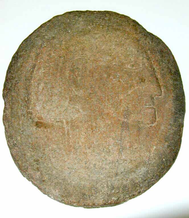 Image couleur d’un visage de profil sculpté sur une roche ovale rouge
