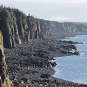 Colour photograph of a gray rock cliff along a shoreline